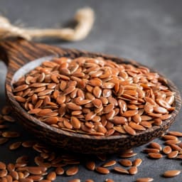 Spoonful of flax seeds on a dark surface