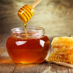 a jar of honey with a wooden spoon next to it